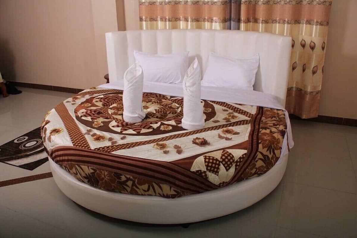 Una cama redonda con un edredón estampado y dos almohadas blancas.