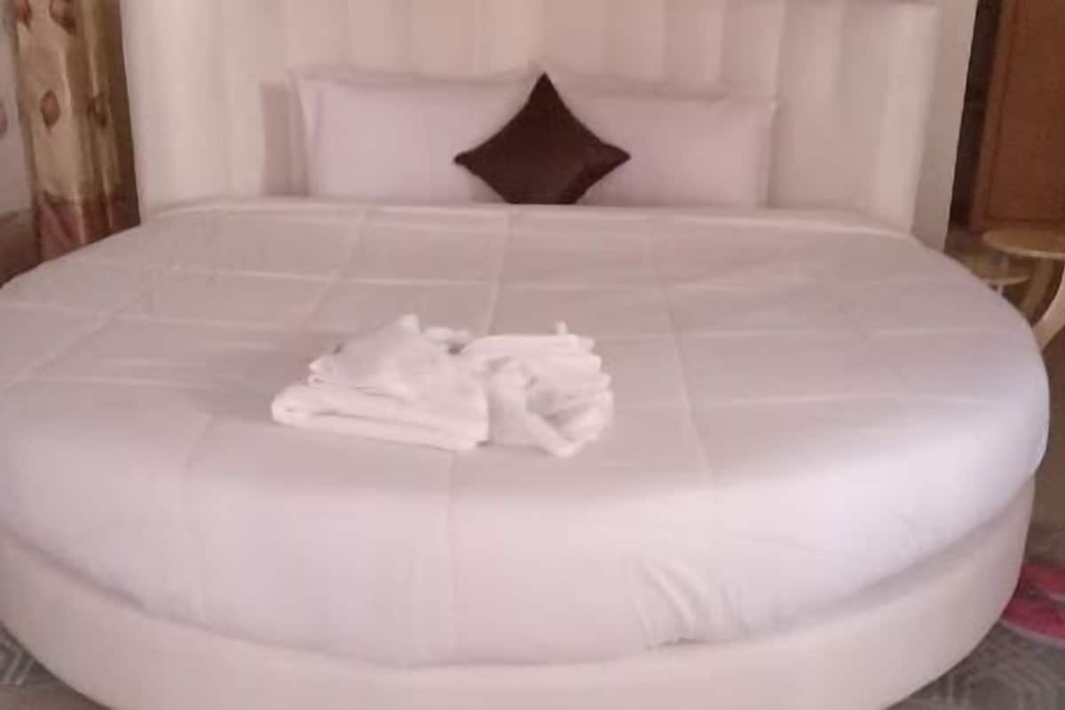 Una cama grande con una toalla blanca doblada cuidadosamente y un cojín marrón.