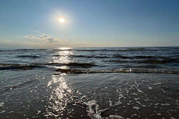A beach with waves and sunlight reflecting on the water.