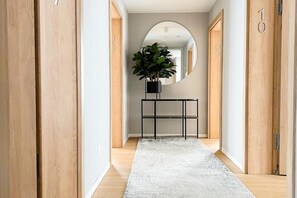 A hallway with wooden doors, a white rug, a console table with a plant, and a mirror on the wall. - Comfortable 2-room studio for 4 people, Dziwnow. (Dziwnów)