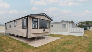 Una casa móvil con un ventanal grande, un porche pequeño y un patio cercado.