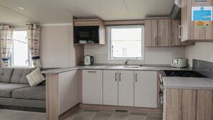 Una cocina compacta equipada con microondas, hervidor, tostadora y lavamanos.