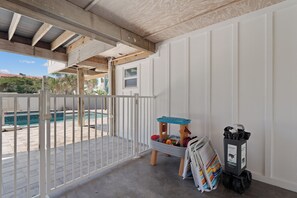 Un balcon avec vue sur la piscine, une petite maison de jeu et un chariot de nettoyage.