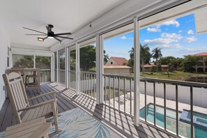 A covered outdoor area with a ceiling fan, a pool, and a view of a residential area.