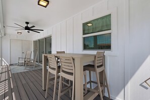 A covered outdoor dining area with a table and chairs, a ceiling fan, and a view through a window. - ☀️ Fun Outdoor Area🐾Pet Friendly🐾Shared Pool + Spa | Monty's Place☀️ (Fort Myers Beach)