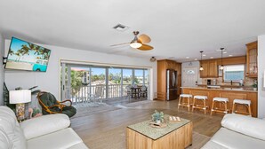 A spacious living room with a large TV, a ceiling fan, and a view to the outside. - ☀️Private Pool, Fun Outdoor Area🐾Pet Friendly🐾Vallie's Villa & Monty's Place☀️ (Fort Myers Beach)