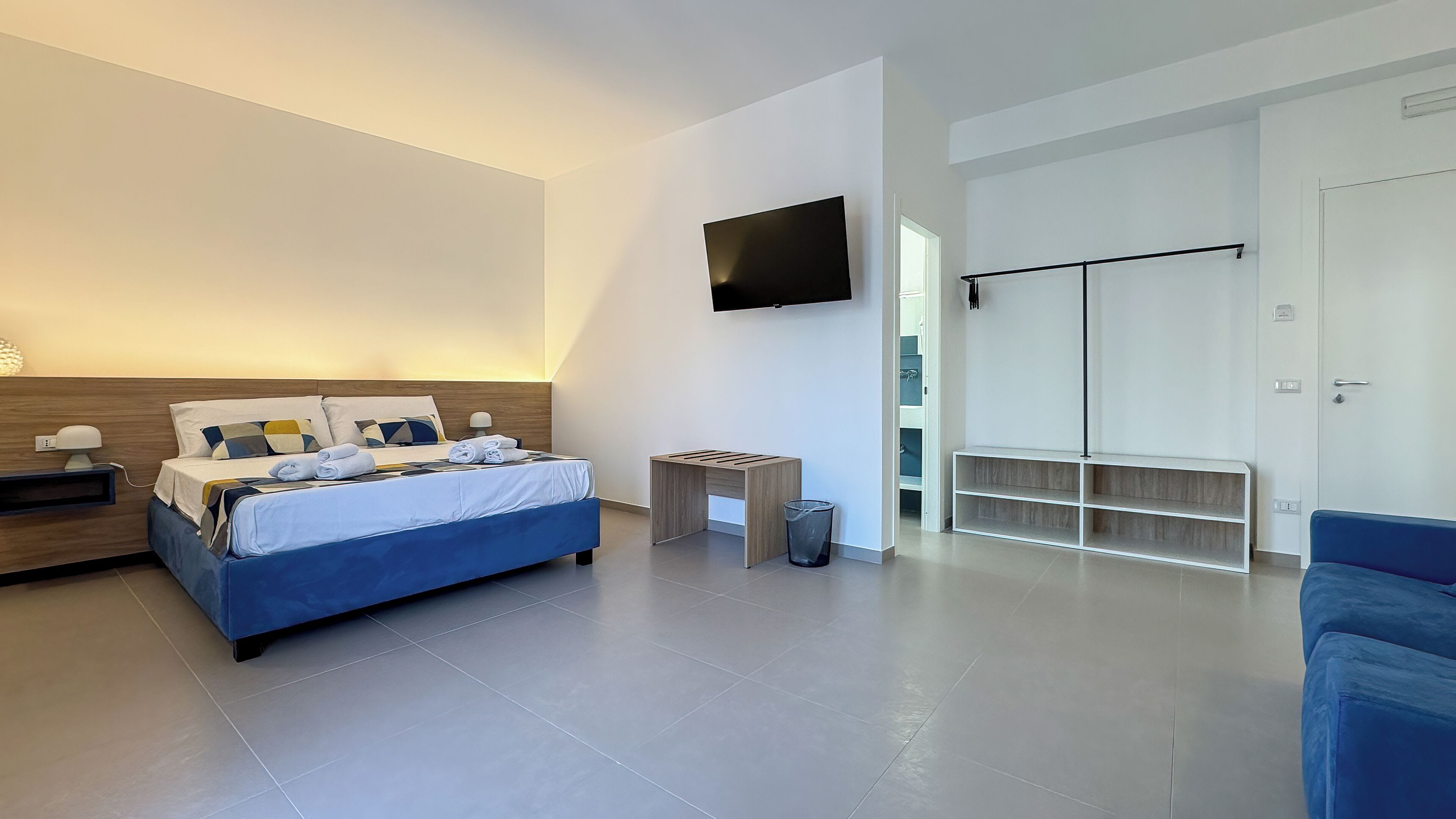 A modern bedroom with a bed, bedside tables, a TV, and a wardrobe.