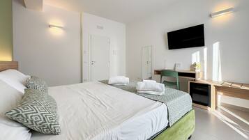 Una habitación de hotel moderna con una cama grande, un escritorio con una silla, un televisor de pantalla plana y un armario.