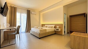 A modern hotel room with a bed, desk, chair, and a TV mounted on the wall. - Tevergad Suite & Rooms (Terrasini)