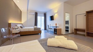 A modern hotel room with a large bed, a desk, a chair, a TV, and a wardrobe. - Tevergad Suite & Rooms (Terrasini)