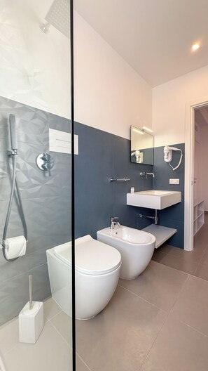 A modern bathroom with a glass partition, a shower, a bidet, a toilet, and a sink. - Tevergad Suite & Rooms (Terrasini)