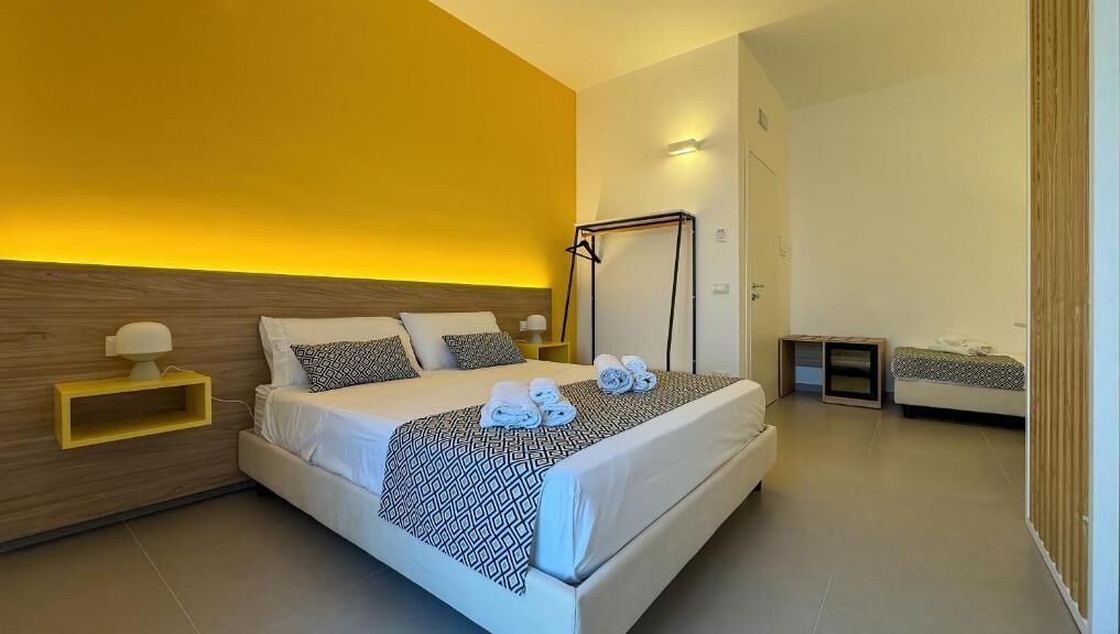 Una camera d'albergo moderna con un letto grande, comodini e una lampada da comodino.