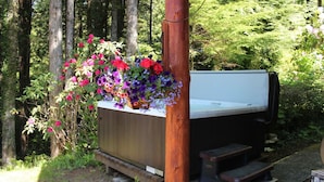 A hot tub with a wooden bench and a flower planter. - Ucluelet/Ocean/Treehouse Cabin - hot tub, kitchen, deck, Roku TV (Alberni Clayoquot Regional District)