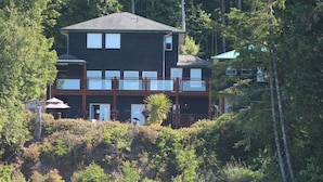 A two-story building with a balcony, surrounded by dense forest. - Ucluelet/Ocean/Treehouse Cabin - hot tub, kitchen, deck, Roku TV (Alberni Clayoquot Regional District)