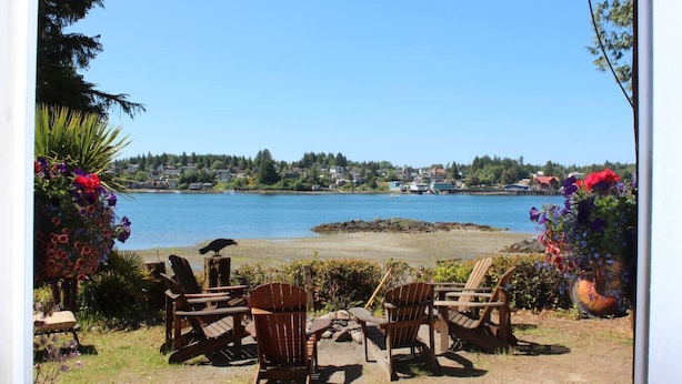 A view of a lake with chairs and flowers on the shore.