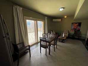 Un comedor con una mesa preparada para cuatro personas, un sofá y un cuadro en la pared.
