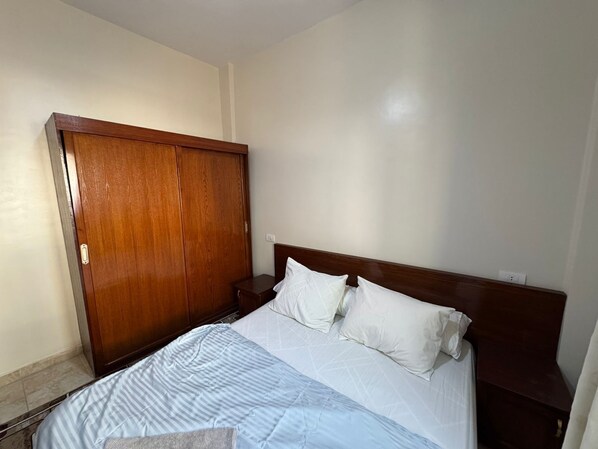 Ein Schlafzimmer mit einem Holzschrank, einem Bett mit weißer Bettwäsche und einem Nachttisch.