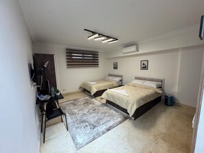 Un dormitorio con dos camas, un escritorio, una silla, una alfombra pequeña y un ventilador de techo.