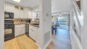 Une cuisine moderne avec des meubles blancs, des appareils en acier inoxydable et un plancher en bois.