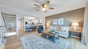 Un salon moderne avec un canapé, une table basse et, au fond, un coin repas.