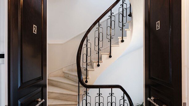 A staircase with a dark wooden finish and a metal railing. - Asty Luxury Apartments (Athens)