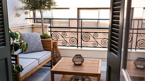A balcony with a wooden sofa, a small table, and decorative items. - Asty Luxury Apartments (Athens)