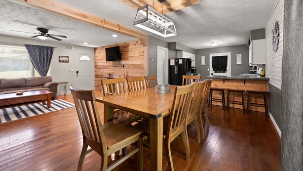 A spacious living area with a wooden dining table and chairs, a sofa, and a kitchen area with a refrigerator and cabinets. - 4 bedroom house WiFi/AC/deck/firepit/grill Laurel Lake/Cumberland Falls, Corbin (Corbin)