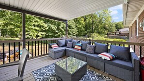 A covered outdoor seating area with a sectional sofa, a glass coffee table, and a patterned rug. - 4 bedroom house WiFi/AC/deck/firepit/grill Laurel Lake/Cumberland Falls, Corbin (Corbin)