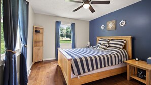 A bedroom with a wooden bed, a nightstand, a ceiling fan, and a window with curtains. - 4 bedroom house WiFi/AC/deck/firepit/grill Laurel Lake/Cumberland Falls, Corbin (Corbin)