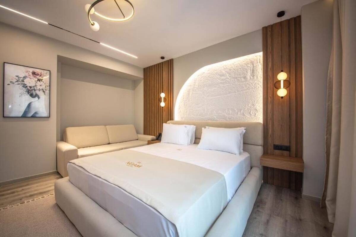 Habitació d'hotel moderna amb un llit gran, un sofà i una làmpada penjant a la paret.