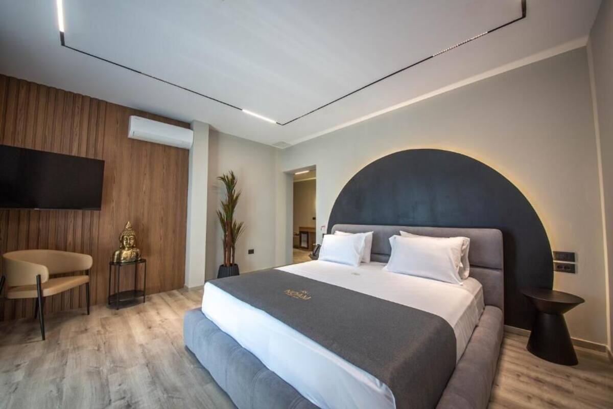 Habitació d'hotel moderna amb un llit gran, un televisor de pantalla plana fixat a la paret, una taula auxiliar petita i una cadira.