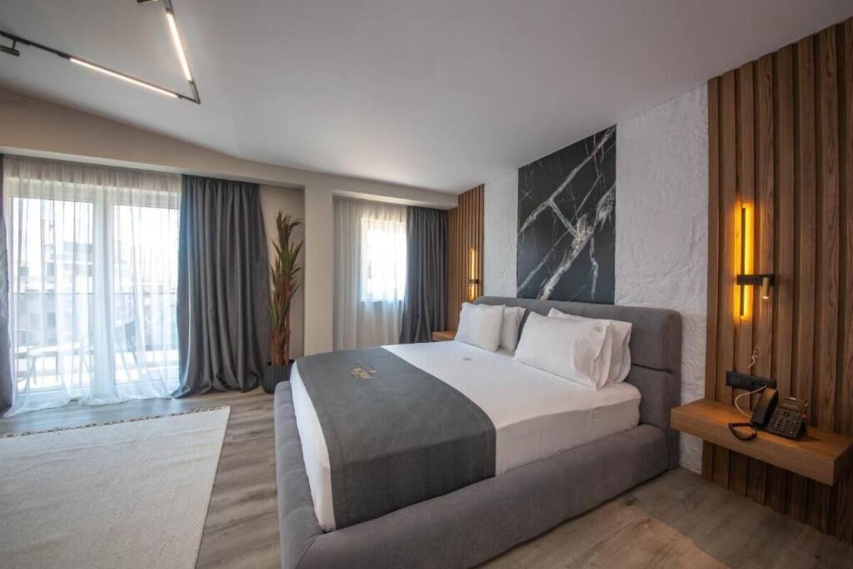 Habitació d'hotel moderna amb un llit gran, una obra d'art de marbre i una paret decorativa de fusta.