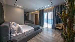 Moderni hotellihuone, jossa on suuri sänky, sohva, tuoli ja ruukkukasvi.
