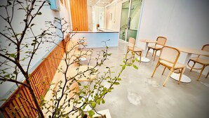 A modern interior with a wooden slatted wall, a central table with chairs, and a view of a staircase. - Momento Hotel and Cafe (Khon Kaen)