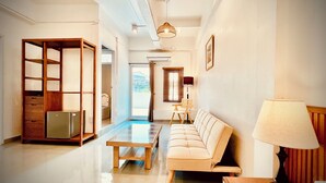 A modern living room with a sofa, a coffee table, a lamp, and a wooden cabinet. - Momento Hotel and Cafe (Khon Kaen)