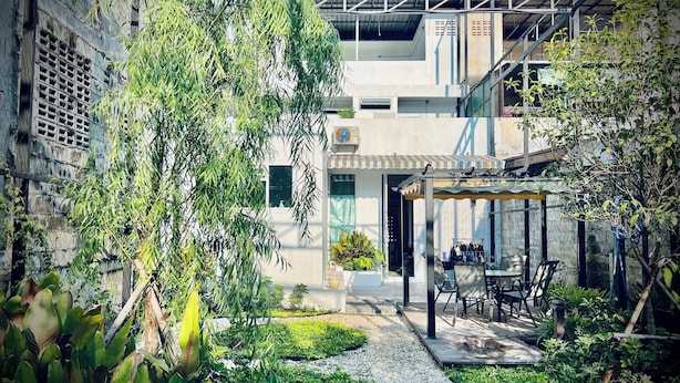 A courtyard with a seating area, a covered outdoor space, and a building with a modern design. - Momento Hotel and Cafe (Khon Kaen)
