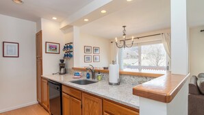 A kitchen with wooden cabinets, a dishwasher, a sink, and a window with a view of the outside. - Cozy Sugarbush condo w/ ski-in/ski-out (Warren)
