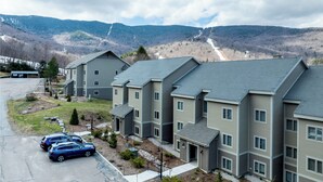 A row of modern multi-story buildings with a parking area in front. - Cozy Sugarbush condo w/ ski-in/ski-out (Warren)