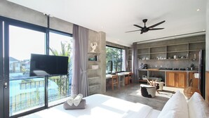 A modern hotel room with a large bed, a balcony with a TV, a kitchenette, and a ceiling fan. - Blanca8 - 17 - Apartment with a kitchen (Canggu)