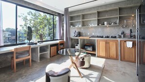 A modern kitchen with large windows, a glass dining table, wooden cabinets, and a view of the outdoors. - Blanca8 - 17 - Apartment with a kitchen (Canggu)