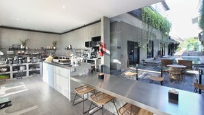 A modern kitchen with a central island, bar area with stools, and a seating area with tables and chairs. - Blanca8 - 17 - Apartment with a kitchen (Canggu)