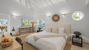 A spacious bedroom with a large bed, a wooden desk, and a dining table with fruit. - Captian's Suite @ Yacht Club, Large Suite 5-minute walk from Grace Bay Beach (Providenciales)