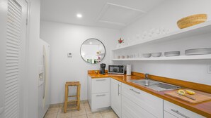A modern kitchen with white cabinets, a wooden countertop, and a built-in microwave. - Captian's Suite @ Yacht Club, Large Suite 5-minute walk from Grace Bay Beach (Providenciales)