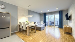 A modern living space with a dining area, sofa, and balcony. - Apartamenty Sun & Snow Blue Baltic (Pogorzelica)