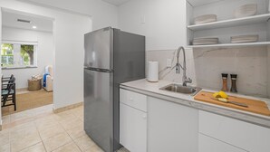 Eine moderne Küche mit Edelstahlkühlschrank, weißen Schränken und einer Marmor-Spritzschutzwand.