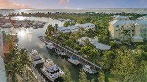 Un port de plaisance où sont amarrés de nombreux bateaux, entouré d’une végétation luxuriante et de bâtiments résidentiels.