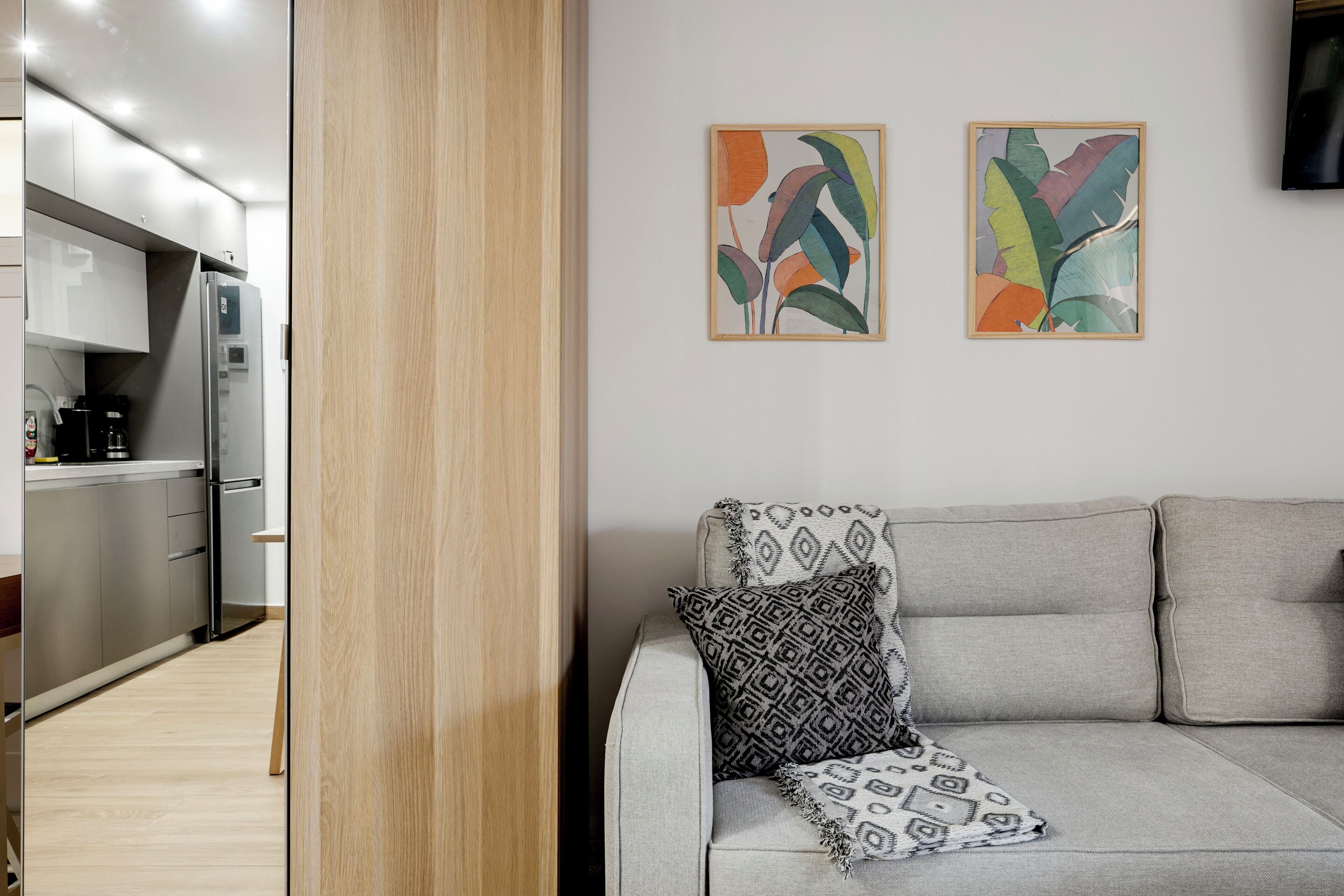 A modern living room with a grey sofa, a patterned throw pillow, and two abstract paintings on the wall.