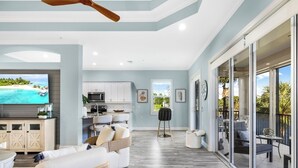 A spacious living area with a kitchen, a dining area, and a balcony with outdoor furniture. - Luxury Waterfront Rental with wraparound water views at Miromar Lakes, (Miromar Lakes)