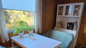 A dining area with a white table and four grey chairs, a wooden ceiling, and a view of trees outside. - Cozy TinyHouse with garden in the nature park (Rorodt)