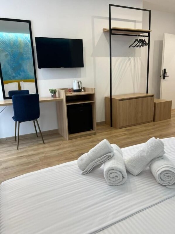 A hotel room with a bed, a desk, a chair, a television, a coffee maker, and a wardrobe.